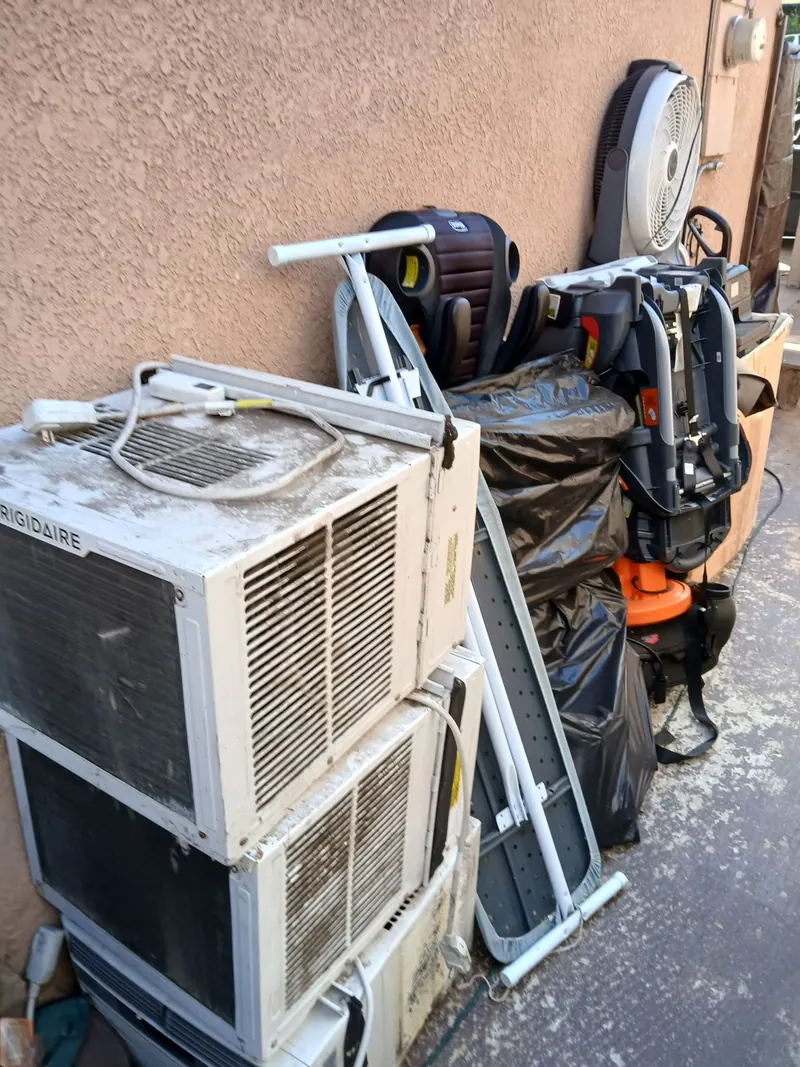 Old window air conditioners; a bike and household junk stacked for pickup